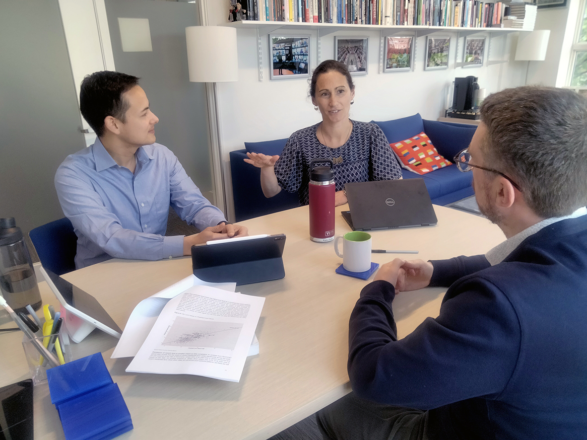 Three researchers in discussion around a table